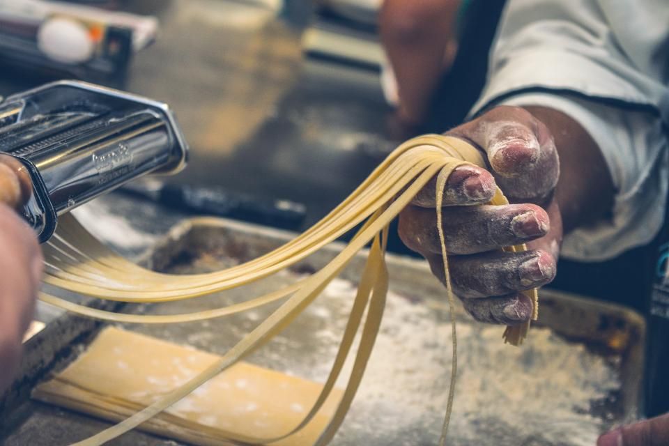 Manos estirando pasta fresca recién hecha